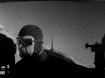 Movie still from “Hell's Angels” (1930), directed by Edmund Goulding – A man in a hat and sunglasses is standing in front of an airplane; Close Up shot, Low angle