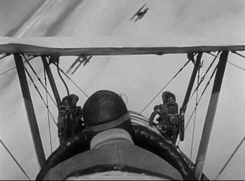 Movie still from “Hell's Angels” (1930), directed by Edmund Goulding – An old photo of a man flying a biplane; Close Up shot, Low angle