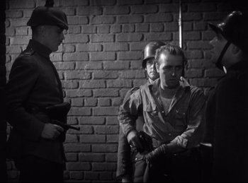 Movie still from “Hell's Angels” (1930), directed by Edmund Goulding – A black and white photo of a group of men in uniform; Medium shot, Over the shoulder angle