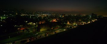 Movie still from “Hellboy” (2019), directed by Neil Marshall – An aerial view of a city at night with cars driving down the road; Extreme Wide shot, High angle