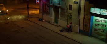 Movie still from “Hellboy” (2019), directed by Neil Marshall – A man sitting on the side of the street at night; Wide shot, High angle
