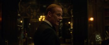 Movie still from “Hellboy” (2019), directed by Neil Marshall – A man in a suit and tie standing in a room; Close Up shot, Over the shoulder angle