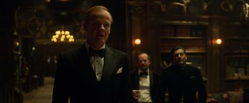 Movie still from “Hellboy” (2019), directed by Neil Marshall – A man in a tuxedo standing next to another man in a suit; Medium shot, Low angle