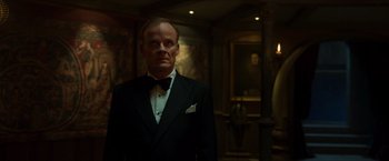 Movie still from “Hellboy” (2019), directed by Neil Marshall – A man in a tuxedo standing in front of a painting; Medium shot, Low angle