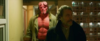 Movie still from “Hellboy” (2019), directed by Neil Marshall – A man and a man with a red mask; Medium shot, Over the shoulder angle