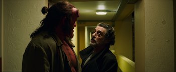 Movie still from “Hellboy” (2019), directed by Neil Marshall – A man in a black jacket and a red demon face; Medium shot, Over the shoulder angle