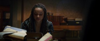 Movie still from “Hellboy” (2019), directed by Neil Marshall – A woman with dreadlocks looking down at a book; Medium shot, Over the shoulder angle