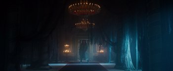 Movie still from “Hellboy” (2019), directed by Neil Marshall – A person standing in a room with candles on the ceiling; Extreme Wide shot, Low angle