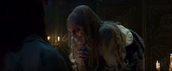 Movie still from “Hellboy” (2019), directed by Neil Marshall – A man with long white hair is eating something in a dark room; Close Up shot, Over the shoulder angle