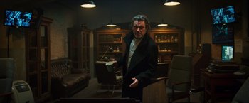 Movie still from “Hellboy” (2019), directed by Neil Marshall – A man holding a coffee cup in a room with bookcases; Medium shot, Low angle