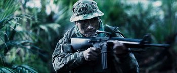 Movie still from “Hellboy” (2019), directed by Neil Marshall – A man holding a gun while standing in the woods; Medium shot, Low angle