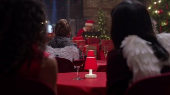 Movie still from “Under the Christmas Tree” (2021), directed by Lisa Rose Snow – People are sitting at a table with a red table cloth; Medium shot, Over the shoulder angle
