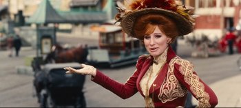 Movie still from “Hello, Dolly!” (1969), directed by Gene Kelly – A woman dressed in a victorian costume with a feather hat; Close Up shot, Over the shoulder angle