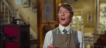 Movie still from “Hello, Dolly!” (1969), directed by Gene Kelly – A man wearing an apron and holding a pair of chopsticks; Medium shot, Low angle