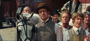 Movie still from “Hello, Dolly!” (1969), directed by Gene Kelly – A group of men standing next to each other on horses; Medium shot, Low angle