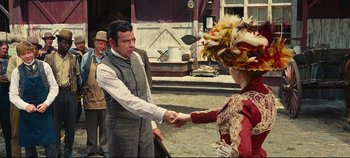Movie still from “Hello, Dolly!” (1969), directed by Gene Kelly – A man and a woman shaking hands in front of other people; Medium shot, Over the shoulder angle