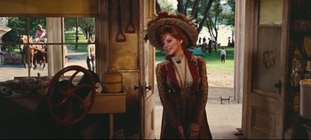 Movie still from “Hello, Dolly!” (1969), directed by Gene Kelly – A beautiful woman in a hat standing in front of an open door; Medium shot, Over the shoulder angle