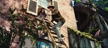 Movie still from “Hello, Dolly!” (1969), directed by Gene Kelly – A man standing on top of a ladder next to a woman; Wide shot, Low angle