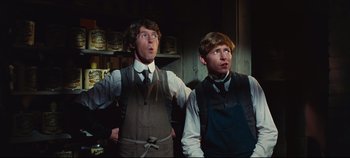 Movie still from “Hello, Dolly!” (1969), directed by Gene Kelly – Two young men standing next to each other in front of a wall; Medium shot, Low angle