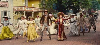 Movie still from “Hello, Dolly!” (1969), directed by Gene Kelly – A group of people dressed in period costumes; Wide shot, Low angle