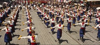 Movie still from “Hello, Dolly!” (1969), directed by Gene Kelly – A group of people dressed in blue and red are dancing; Wide shot, High angle