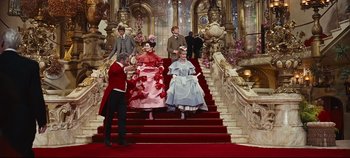 Movie still from “Hello, Dolly!” (1969), directed by Gene Kelly – A group of people sitting on top of a set of stairs; Wide shot, Low angle