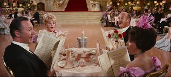 Movie still from “Hello, Dolly!” (1969), directed by Gene Kelly – A group of people sitting at a dinner table; Medium shot, High angle