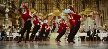 Movie still from “Hello, Dolly!” (1969), directed by Gene Kelly – A group of people in red and black outfits performing a dance; Wide shot, Low angle