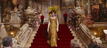 Movie still from “Hello, Dolly!” (1969), directed by Gene Kelly – A woman in a gold dress on a red staircase; Wide shot, Low angle