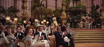 Movie still from “Hello, Dolly!” (1969), directed by Gene Kelly – A group of people sitting at a table with food; Wide shot, High angle