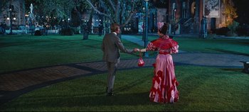 Movie still from “Hello, Dolly!” (1969), directed by Gene Kelly – A man and a woman holding hands in a park; Wide shot, Over the shoulder angle