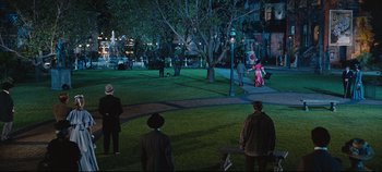 Movie still from “Hello, Dolly!” (1969), directed by Gene Kelly – A group of people standing in a park at night; Extreme Wide shot, High angle