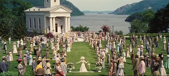 Movie still from “Hello, Dolly!” (1969), directed by Gene Kelly – A group of people standing in a field near a body of water; Extreme Wide shot, High angle