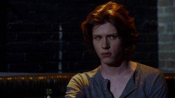 Movie still from “Hellraiser: Revelations” (2011), directed by Víctor Garcia – A man with long red hair sitting in front of a bottle; Close Up shot, Over the shoulder angle