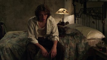 Movie still from “Hellraiser: Revelations” (2011), directed by Víctor Garcia – A person sitting on a bed in a room; Medium shot, Low angle
