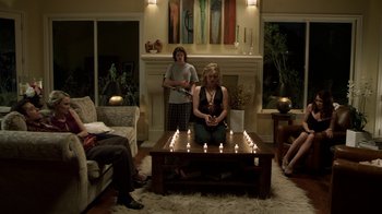 Movie still from “Hellraiser: Revelations” (2011), directed by Víctor Garcia – A group of people sitting around a coffee table with lit candles on it; Wide shot, High angle