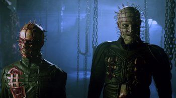 Movie still from “Hellraiser: Revelations” (2011), directed by Víctor Garcia – A couple of people that are standing up in a room; Medium shot, Low angle