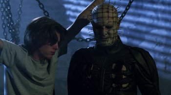 Movie still from “Hellraiser: Revelations” (2011), directed by Víctor Garcia – A man is putting a face mask on a person; Medium shot, Low angle