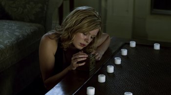 Movie still from “Hellraiser: Revelations” (2011), directed by Víctor Garcia – A woman is looking at a candle on a table; Medium shot, High angle