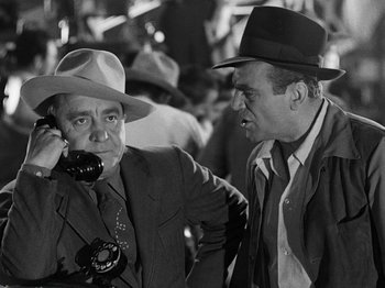 Movie still from “Hellzapoppin'” (1941), directed by H.C. Potter – Two men in suits and hats talking on a cell phone; Medium shot, Over the shoulder angle