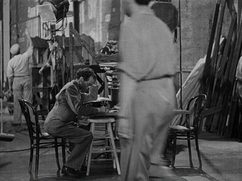 Movie still from “Hellzapoppin'” (1941), directed by H.C. Potter – A black and white photo of a man sitting at a table; Wide shot, High angle