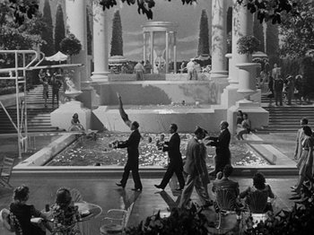 Movie still from “Hellzapoppin'” (1941), directed by H.C. Potter – A black and white photo of people walking in front of a fountain; Extreme Wide shot, High angle