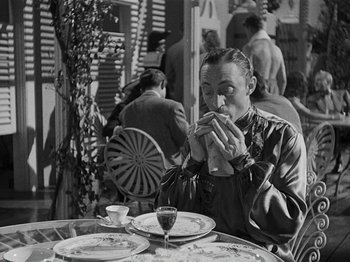 Movie still from “Hellzapoppin'” (1941), directed by H.C. Potter – A black and white photo of a man sitting at a table eating; Medium shot, Over the shoulder angle