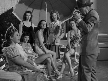 Movie still from “Hellzapoppin'” (1941), directed by H.C. Potter – A man taking a picture of a group of women; Medium shot, Over the shoulder angle