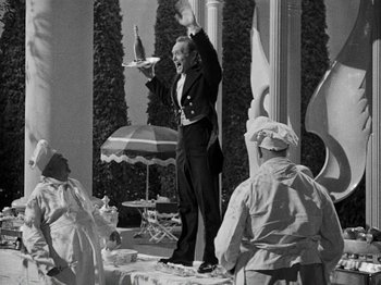 Movie still from “Hellzapoppin'” (1941), directed by H.C. Potter – A man holding a tray in the middle of an outdoor stage; Medium shot, Low angle