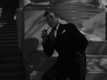 Movie still from “Hellzapoppin'” (1941), directed by H.C. Potter – A black and white photo of a man smoking a pipe; Medium shot, High angle