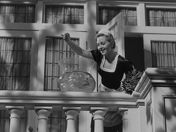 Movie still from “Hellzapoppin'” (1941), directed by H.C. Potter – An old photo of a woman standing on a balcony with a fish bowl; Medium shot, Low angle