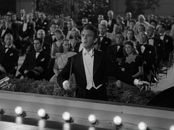 Movie still from “Hellzapoppin'” (1941), directed by H.C. Potter – A man in a tuxedo standing in front of an audience; Medium shot, Low angle