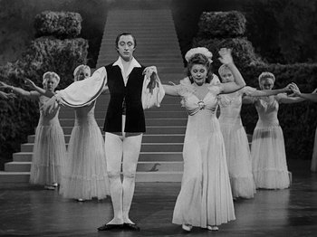 Movie still from “Hellzapoppin'” (1941), directed by H.C. Potter – A man and a woman are standing in front of a group of dancers; Wide shot, High angle