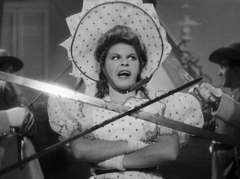 Movie still from “Hellzapoppin'” (1941), directed by H.C. Potter – A woman holding a pair of fencing swords in her hands; Medium shot, Low angle